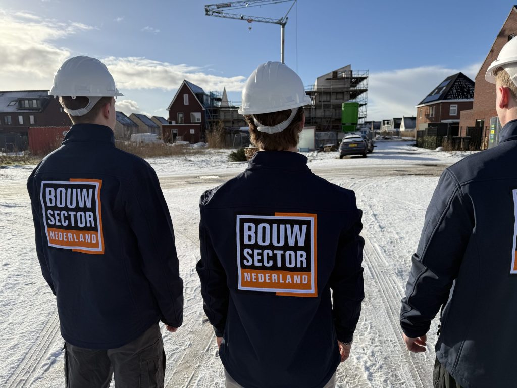 Vakmensen van Bouwsector Nederland in bedrijfsjas bij nieuwbouwwoningen in aanbouw in de winter